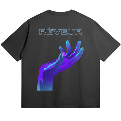 Oversized black streetwear t-shirt “REACH” by RÊVEUR — minimalist futuristic design featuring a neon purple hand reaching upward. Premium 305g cotton.