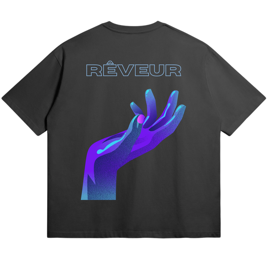 Oversized black streetwear t-shirt “REACH” by RÊVEUR — minimalist futuristic design featuring a neon purple hand reaching upward. Premium 305g cotton.